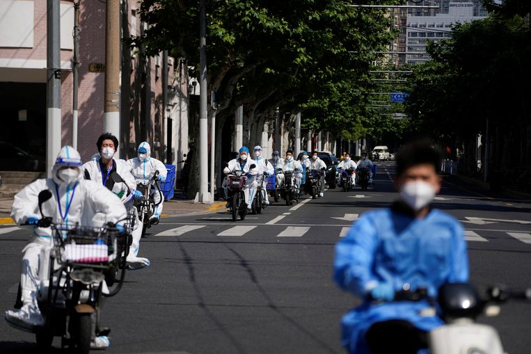 Werknemers rijden in beschermende covidkleding door Shanghai tijdens de lockdown, 18 mei.  Beeld Aly Song / Reuters 
