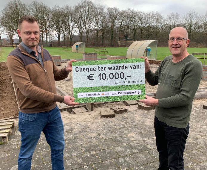 Roy Wiggers (links) overhandigt Jos Elshof (rechts) de cheque op de locatie waar het boardingveld wordt aangelegd.
