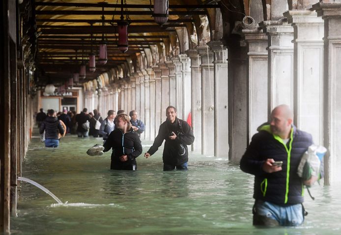 Toeristen waden door het water op het ondergelopen San Marco-plein.