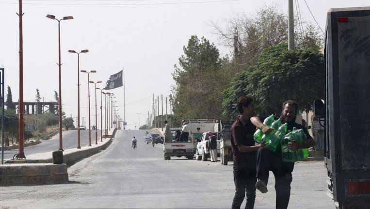 Burgers in de straten van Raqqa, met op de achtergrond een IS-vlag. Beeld reuters