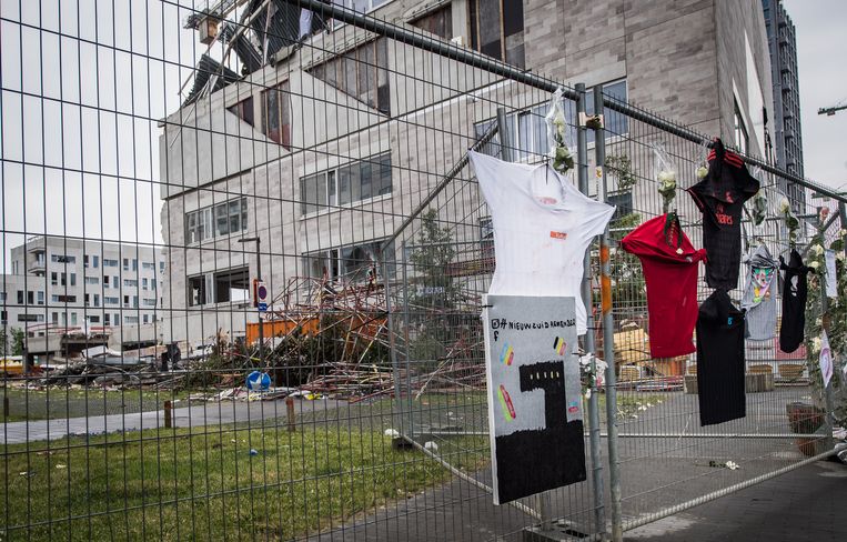 Aan de ingestorte school hangen bloemen, tekeningen en T-shirts om de vijf omgekomen arbeiders te herdenken. Beeld Joel Hoylaerts / Photo News