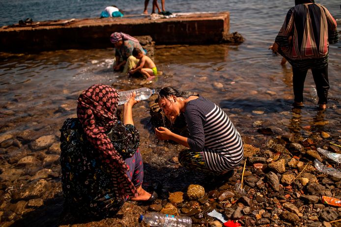 Op een strand nabij de hoofdstad Mytilene helpen vrouwen elkaar bij het wassen van hun haar.