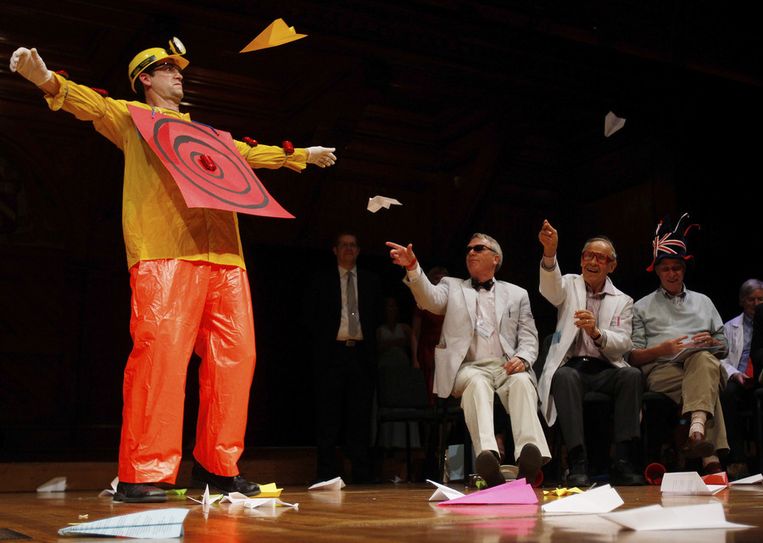 Het werpen van papieren vliegtuigjes op een menselijk doelwit is een van de vele tradities bij de uitreiking van de Ig Nobels. De ruim duizend toeschouwers in de zaal werpen ook mee. Beeld REUTERS