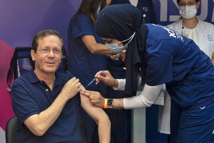 Israeli President Isaac Herzog receives a third dose of the Pfizer/BioNTech Covid-19 vaccine while his wife, Michal (L), reacts, at Sheba Medical Center in Ramat Gan on July 30, 2021, launching the Jewish state's campaign to give booster shots to people aged over 60. (Photo by Maya Alleruzzo / POOL / AFP)