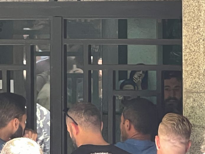 The 42-year-old Bassam al-Sheikh Hussein (right, bearded and behind the door of the bank) listens to the negotiators.