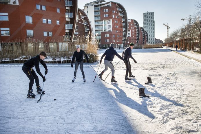 Jongeren spelen ijshockey op een bevroren water in een woonwijk in Den Bosch.