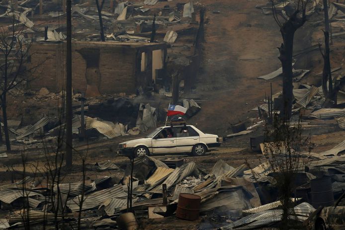 Een auto met de Chileense vlag rijdt door het compleet verwoeste landschap in centraal Chili.