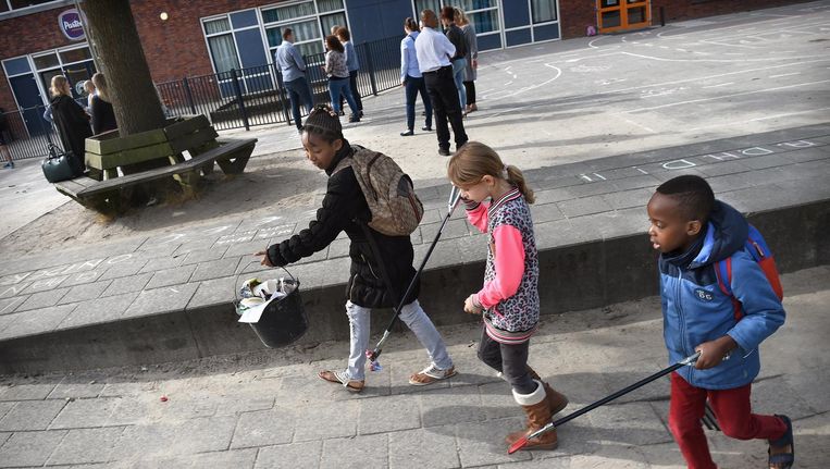 Kinderen maken schoolplein schoon tijdens staking van hun leraren, 27 juni. Beeld Marcel van den Bergh / de Volkskrant