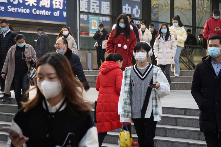 Mensen verlaten een metrostation in Wuhang.  Nu China de strikste maatregelen heeft opgeheven, raast corona door het land. Beeld REUTERS