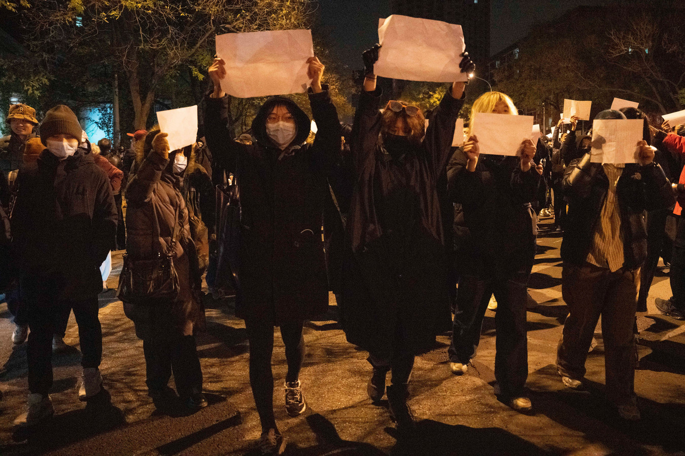 Demonstranten houden witte papieren omhoog en zingen slogans tijdens protesten in China, zondag 27 november 2022.