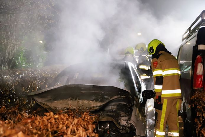 De brandweer blust de brandende auto op de Adelahof in Lienden.