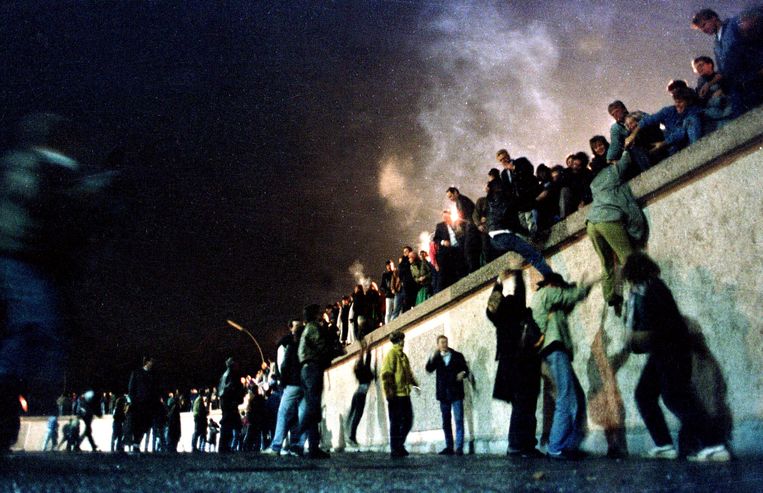 November 1989: mensen klimmen over de Berlijnse Muur nadat bekend raakte dat de grens tussen Oost- en West-Duitsland wordt opgeheven. Beeld REUTERS