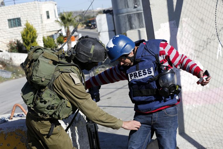 Israëlische soldaat onderzoekt journalist op de Westelijke Jordaanoever. Beeld EPA