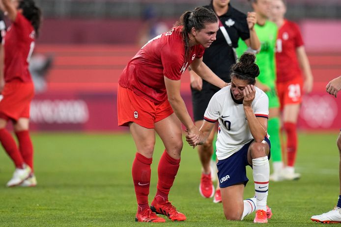 Vanessa Gilles (Canada) helpt de Amerikaanse voetbalster Carli Lloyd overeind.