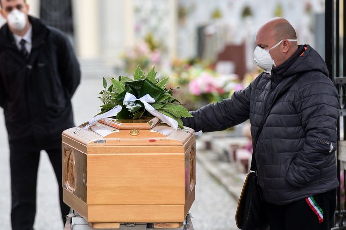 Een man neemt afscheid van zijn bezweken familielid tijdens een begrafenis in Bolgare, Lombardije.