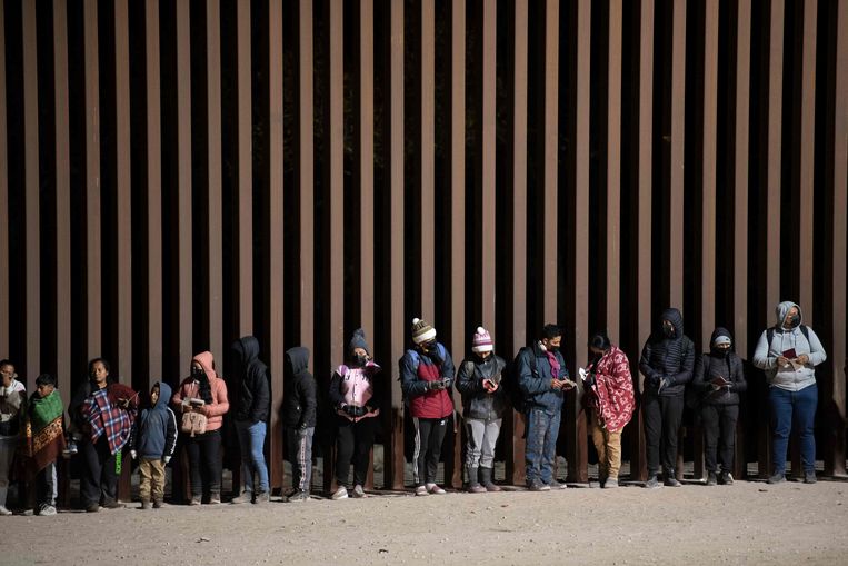 Migranten bij de grensmuur tussen de Amerikaanse staat Arizona en Mexico. Beeld AFP