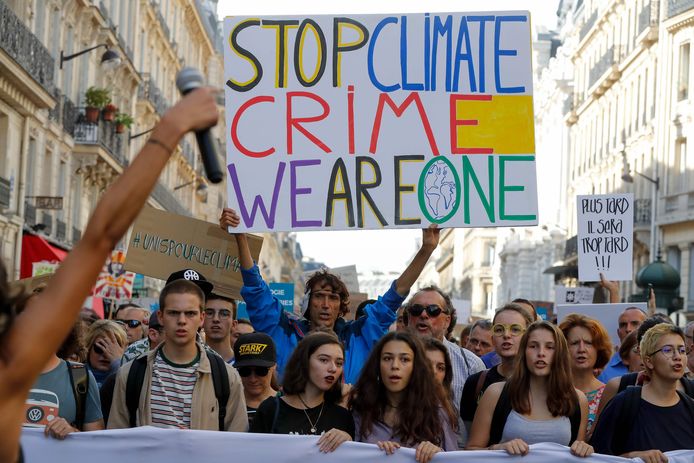 De Franse activist Jean-Baptiste Redde, aka Voltuan (m) loopt met een protestbord met de tekst: "Stop de klimaatmisdaad, wij zijn één" tijdens de Mars tegen klimaatverandering in Parijs.