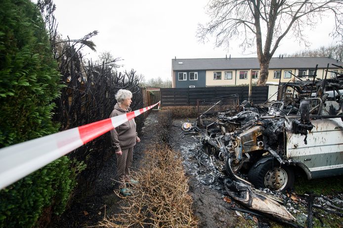Marja Weerts uit Ugchelen bekijkt de enorme schade die de twee campers bij de brand hebben opgelopen. De coniferenhaag van haar tuin moesten er ook aan geloven.