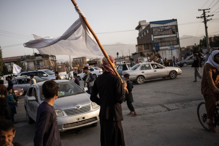 Een jongeman met witte talibanvlag organiseert het verkeer in Kaboel. Beeld Jim Huylebroek for The New York Times