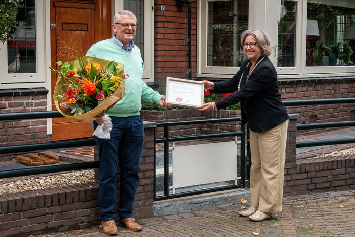 Eltjo Kok wordt door burgemeester als Beste Buur 2020 in het zonnetje gezet met een bos bloemen en een oorkonde