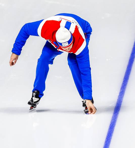 De bondscoach van de Noorse schaatsploeg Sondre Skarli raapt de afgebroken veer van de schaats van Jan Blokhuijsen van het ijs. De veer brak af bij de start van de Nederlandse schaatsploeg.