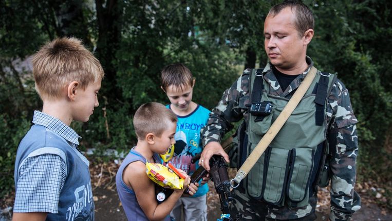 Kinderen inspecteren het geweer van een Oekraïense soldaat in Dzerzjinsk. Beeld epa