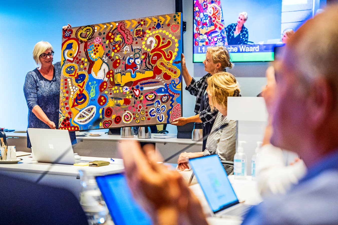Marga Sundermeijer (links) neemt van Ria Bense het schilderij ‘Kleurenschreeuw’ in ontvangst.