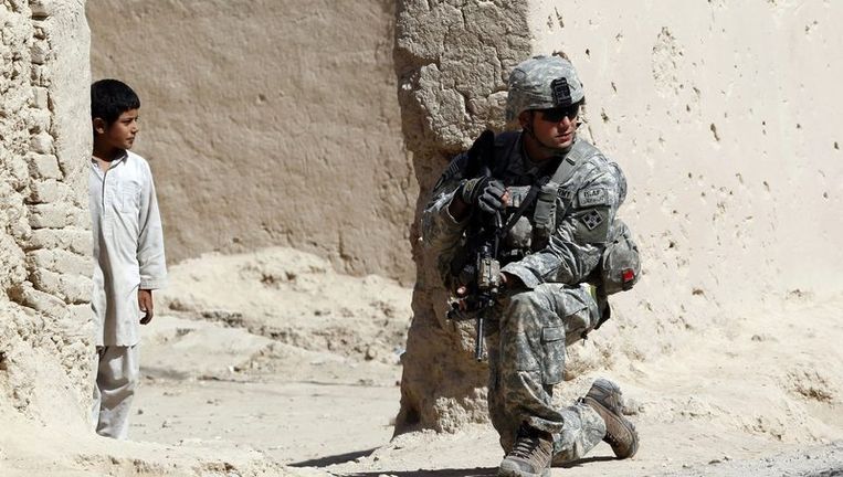 Een jongen kijkt naar een Amerikaanse soldaat in Afghanistan. Beeld reuters