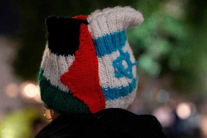 Een vrouw draagt een gebreide muts met de kleuren van de Palestijnse en de Israëlische vlag tijdens de protesten.