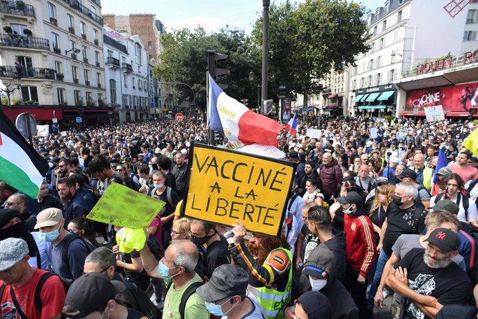 Des manifestants brandissent des banderoles et des pancartes, dont l'une porte la mention "Vacciné à la liberté", lors d'une journée nationale de protestation contre le vaccin obligatoire Covid-19 pour certains travailleurs et l'utilisation obligatoire du pass sanitaire réclamé par le gouvernement français devant le Moulin Rouge à Paris, le 31 juillet 2021.