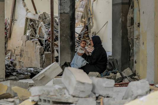 Een Palestijnse vrouw houdt haar baby vast te midden van ruïnes in Gaza-Stad.