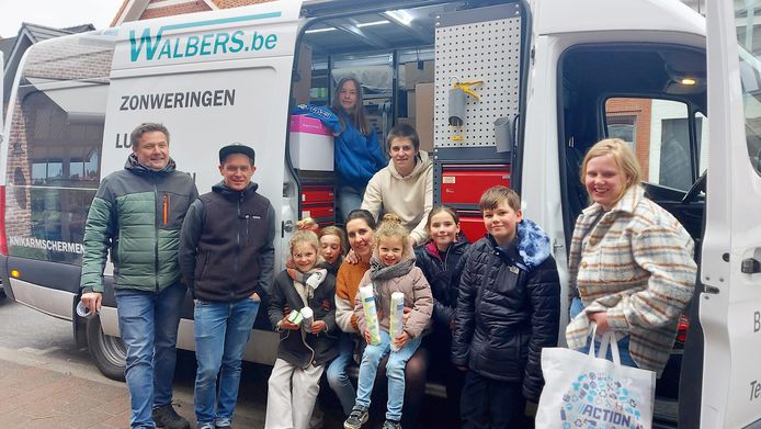 Juf Marieke, Wim en hun kinderen omringd door haar vele helpers aan de camionette vol hulpgoederen.