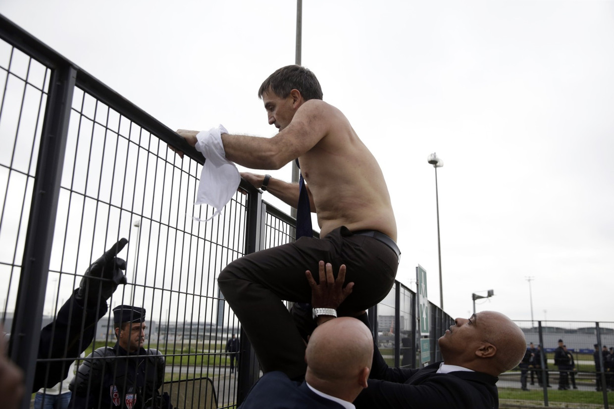 AirFrance-topman Xavier Broseta klimt over een hek om de boze medewerkers te ontvluchten. Beeld afp