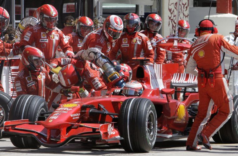 Kimi Räikkönen wil de pits verlaten terwijl de brandslang nog niet is ontkoppeld: een monteur raakt licht gewond en de Fin verliest kostbare seconden. Foto AP/Robert Ghement Beeld 