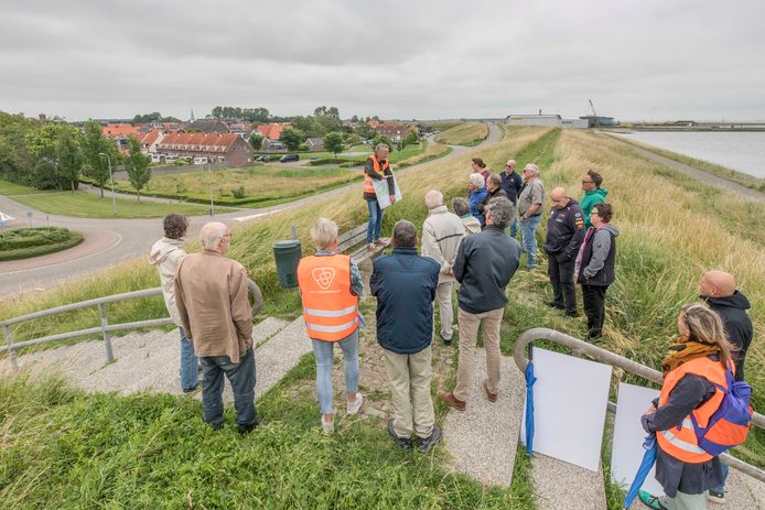 Alex de Smet van Waterschap Scheldestromen (staand op bankje met bord in handen) vertelt de bewoners van Hansweert over de dijkverzwaring en -verhoging (op dit punt 2,75 meter). De rotonde (links) verhuist naar een plekje verderop in de Boomdijk.