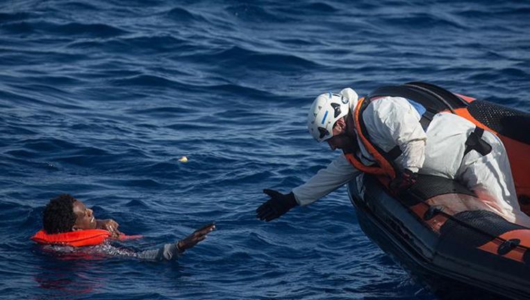 Een reddingswerker redt een vluchteling voor de kust van het Italiaanse eiland Lampedusa in mei 2017 Beeld Getty Images