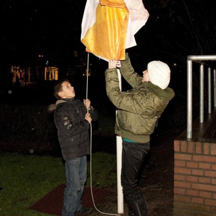 Marnix en Felice hijsen de vlag met het logo van De Brug, het nieuwe gefuseerde protestantse kerkgenootschap. foto Mark Neelemans