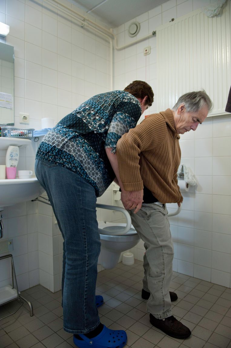 Een  verzorgster helpt een  oudere naar het toilet gaan.  Beeld Hollandse Hoogte