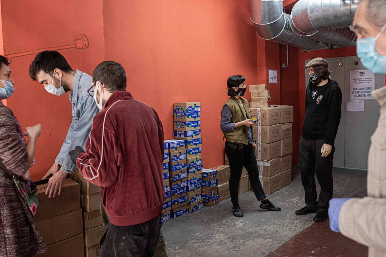 Vrijwilligers van de buurthulp in een wijk in Madrid buigen zich over de verdeling van de binnengekomen goederen voor kwetsbare inwoners.   Beeld Cesar Dezfuli