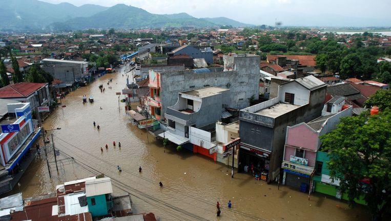 Inwoners waden door een ondergelopen straat in Bandung op het Indonesische eiland Java. Beeld afp