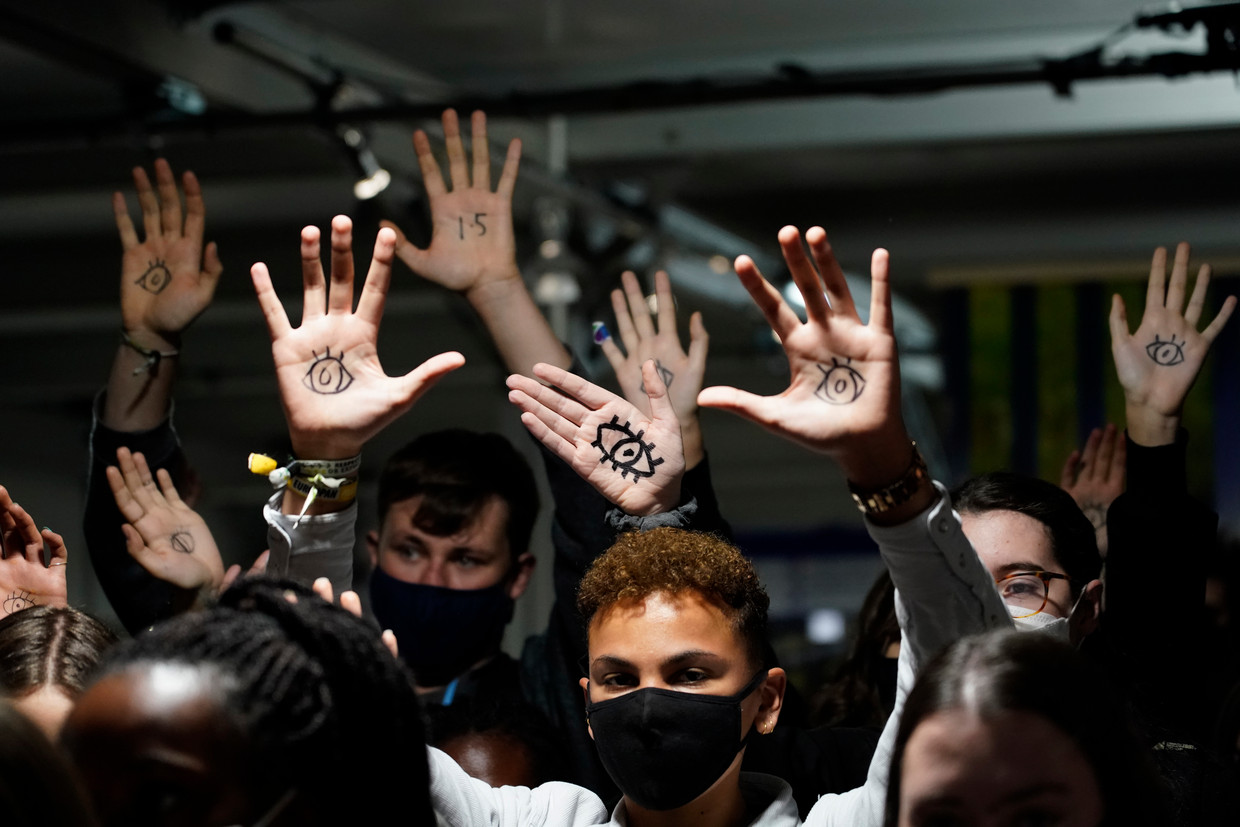 Protesterende jongeren laten in de wandelgangen van de conferentie zien dat ze kritisch meekijken.   Beeld AP