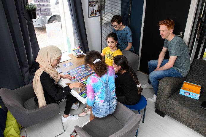 Ilhaam Ouamari (links) doet een bordspel met Eliza, Mareym en Malak, terwijl Harmen Mulder (met bril) en  Jelle Oonk toekijken.
