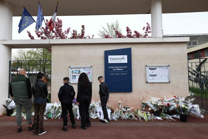 Mensen leggen bloemen neer bij de school van de doodgeslagen 15-jarige jongen.