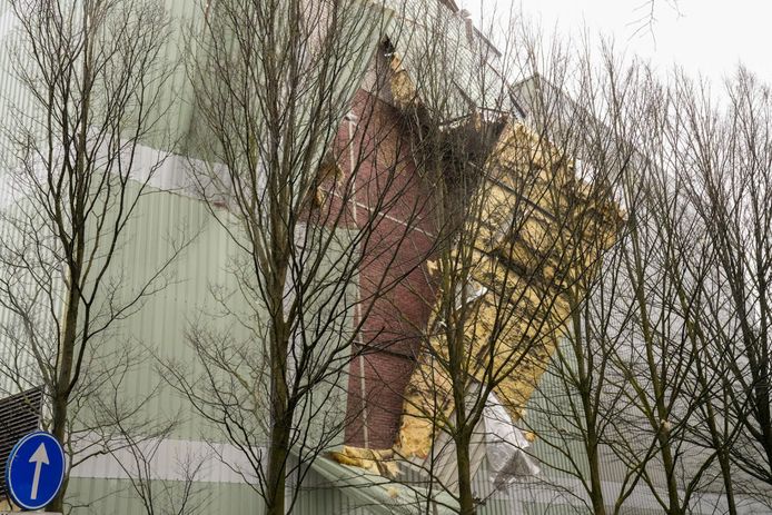 Metalen platen van het bedrijfspand van textielfabriek Raymakers bungelen aan de zijkant van het pund.