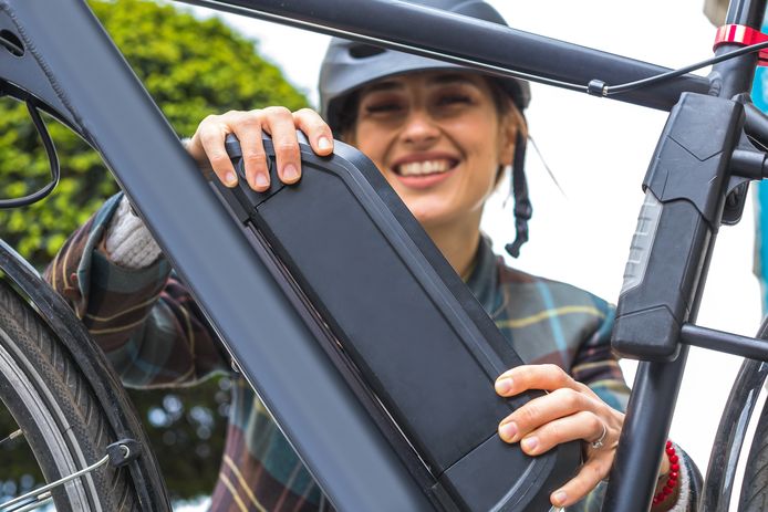 young woman holding an electric bike battery mounted on frame