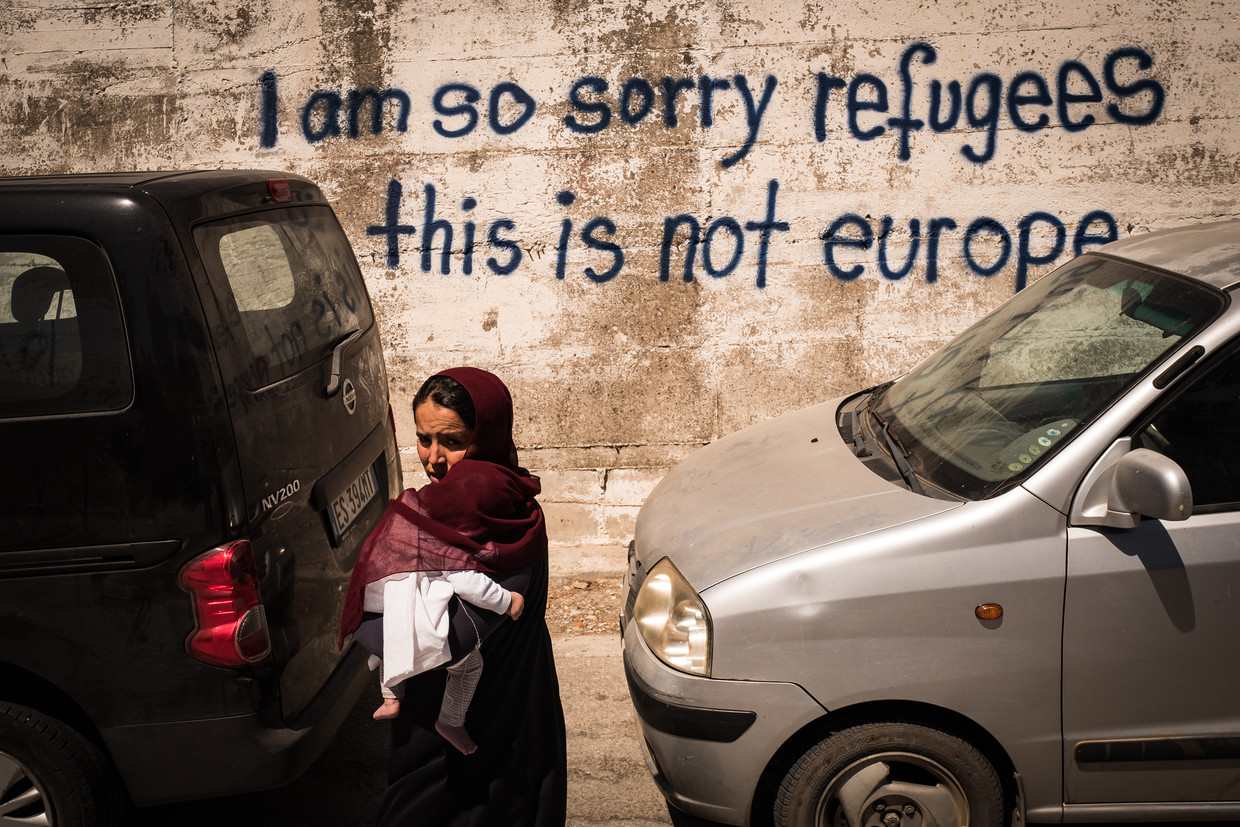 Een Afghaanse draagt haar kind op haar arm net buiten het kamp Moria op het eiland Lesbos. Beeld Nicola Zolin 