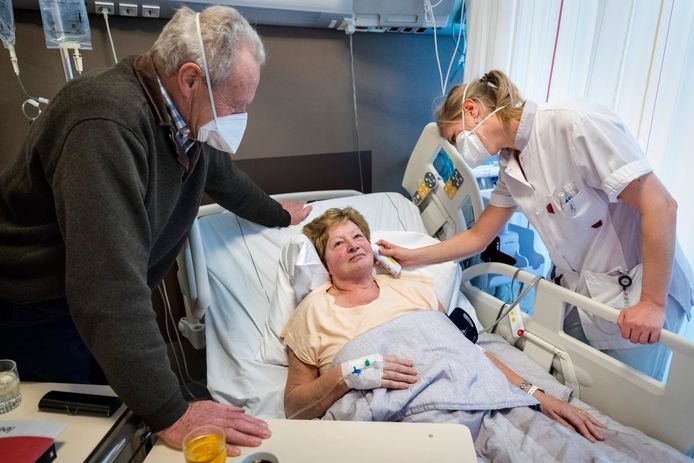 Nederland,  Den Bosch, de grieppoli op het JBZ. fto links Wim van Hal,zijn vrouw en patient Jose van Hal en verpleegkundige Sophie Molthof die de temperatuur controleet met een thermometer in haar oor.
