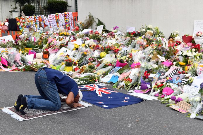 Een man bidt voor de bloemenzee voor de getroffen Al-Noormoskee in Christchurch.