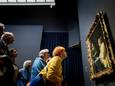 Bezoekers bestuderen Dame en dienstmeid van Johannes Vermeer tijdens de opening van de Vermeertentoonstelling in het Rijksmuseum.