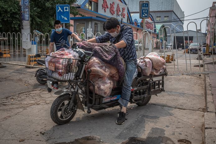 Een man met een scooter vol vlees verlaat  de gesloten Xinfadi markt.